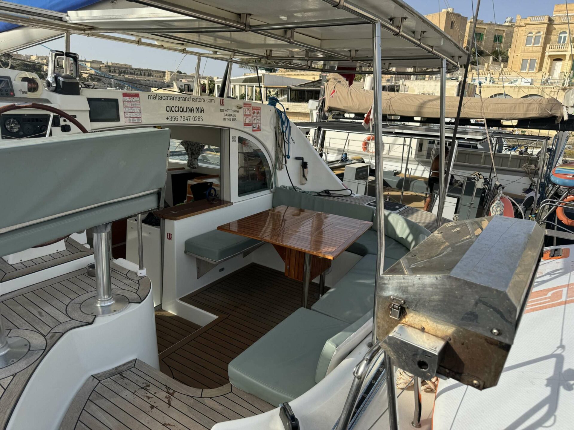 Cockpit table aboard Cicciolina Mia catamaran with Valletta in the background