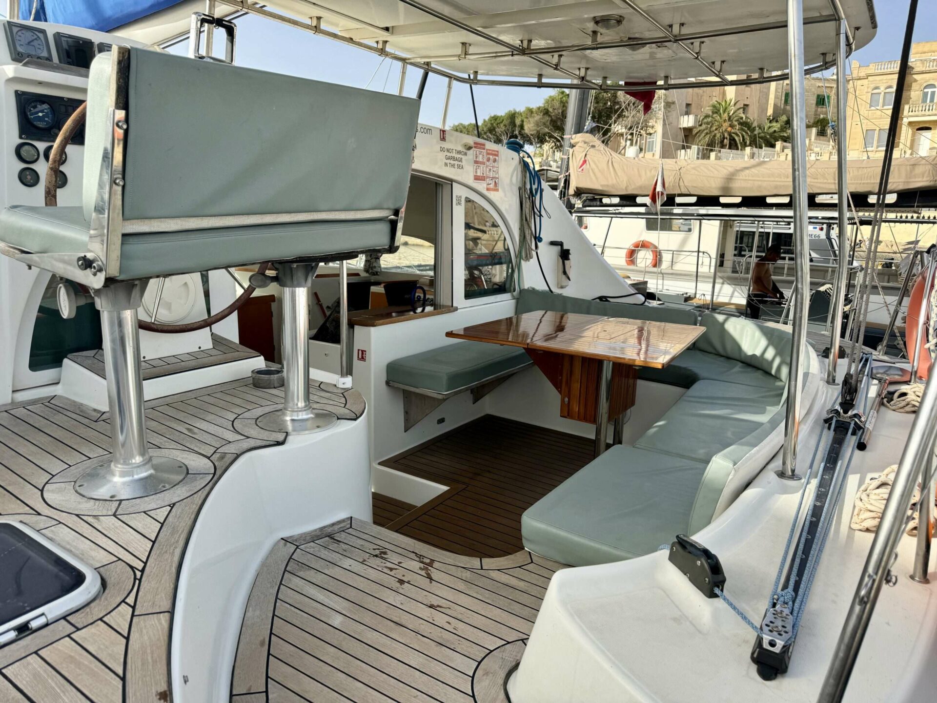 Cicciolina Mia catamaran's cockpit seating and table, moored in a Malta marina