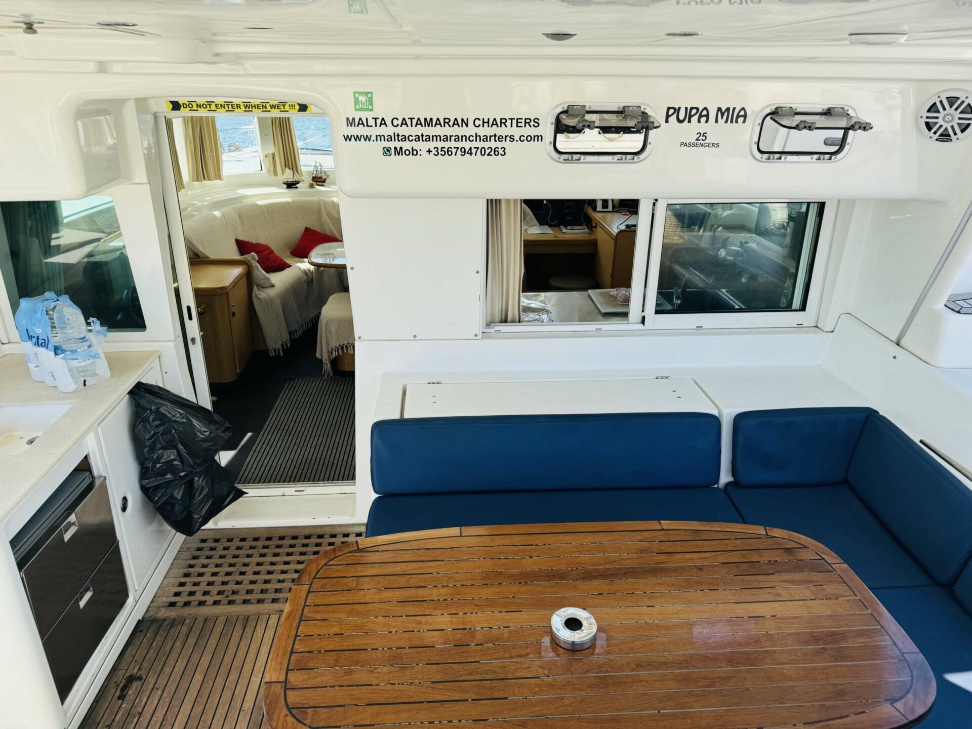 Cockpit seating aboard Pupa Mia catamaran, showing the boat's 25-passenger capacity signage