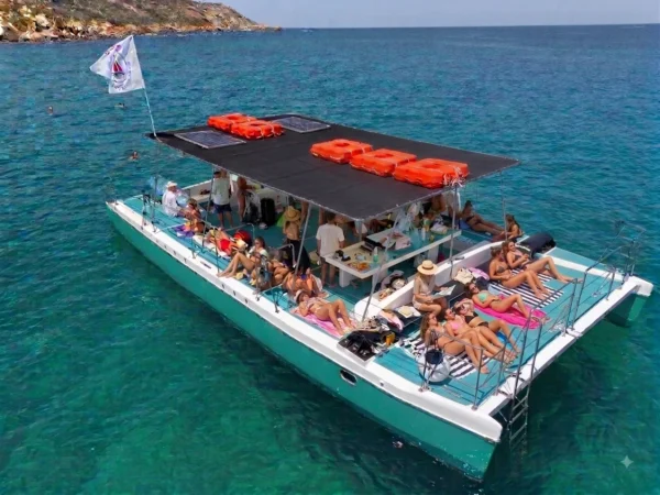 Playtime party catamaran with guests sunbathing on deck off the Maltese coast