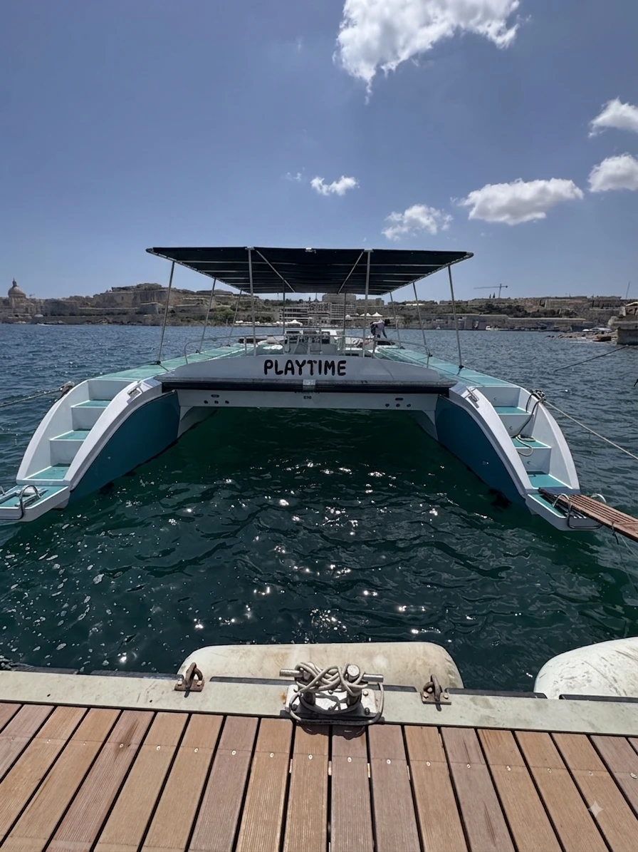 Vista trasera del catamarán Playtime amarrado en el puerto deportivo, mostrando la plataforma de baño.