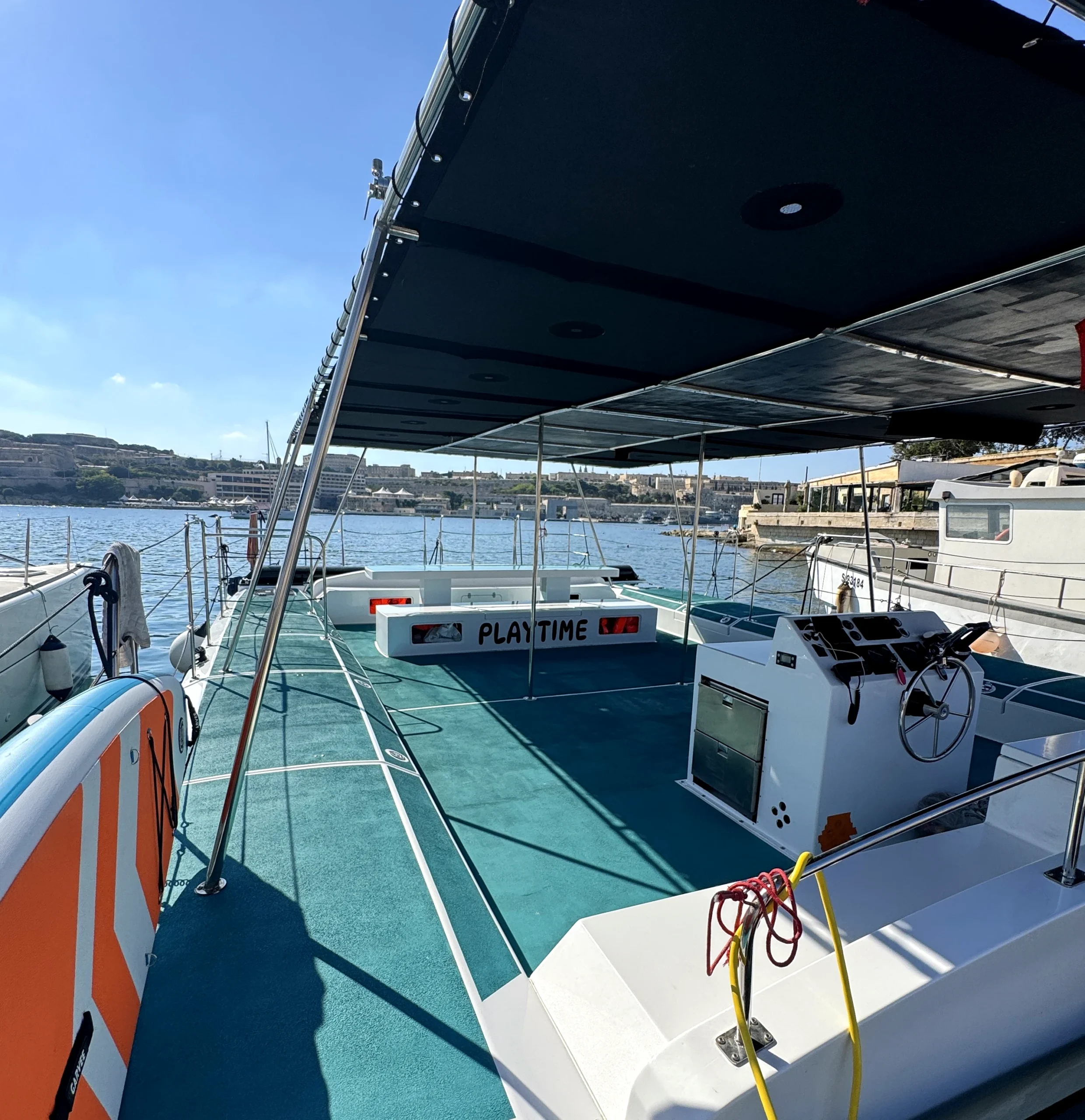 Cubierta abierta y puesto de mando del catamarán Playtime amarrado en el puerto deportivo.